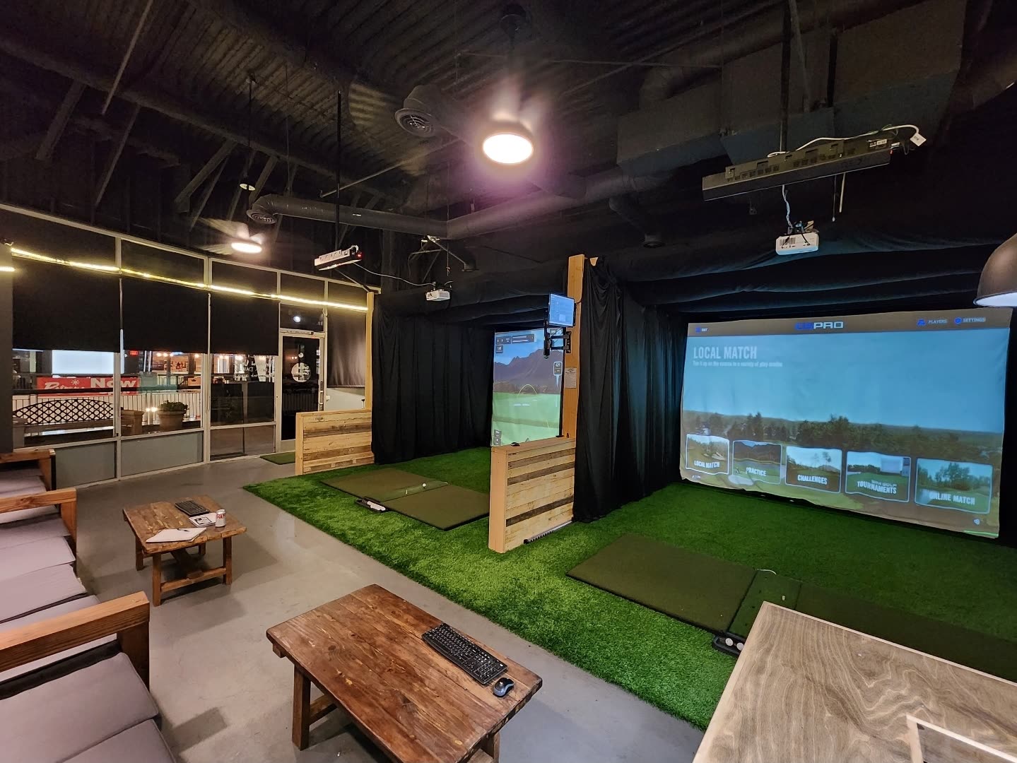 Indoor golf simulator bays with turf, projection screens and lounge seating